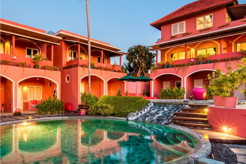 Pink-hued hotel courtyard in early evening, with a circular pool in the centre.